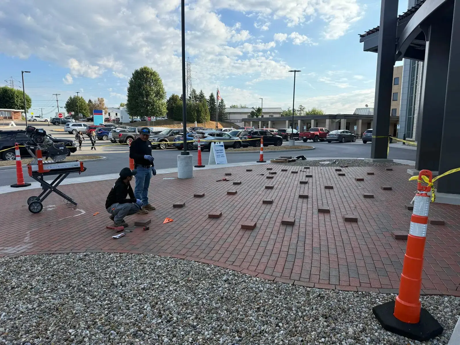 Crew setting brick pavers at a commercial entrance