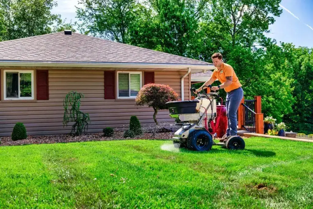 Technician applying fertilizer to an Ohio Valley lawn with a spreader
