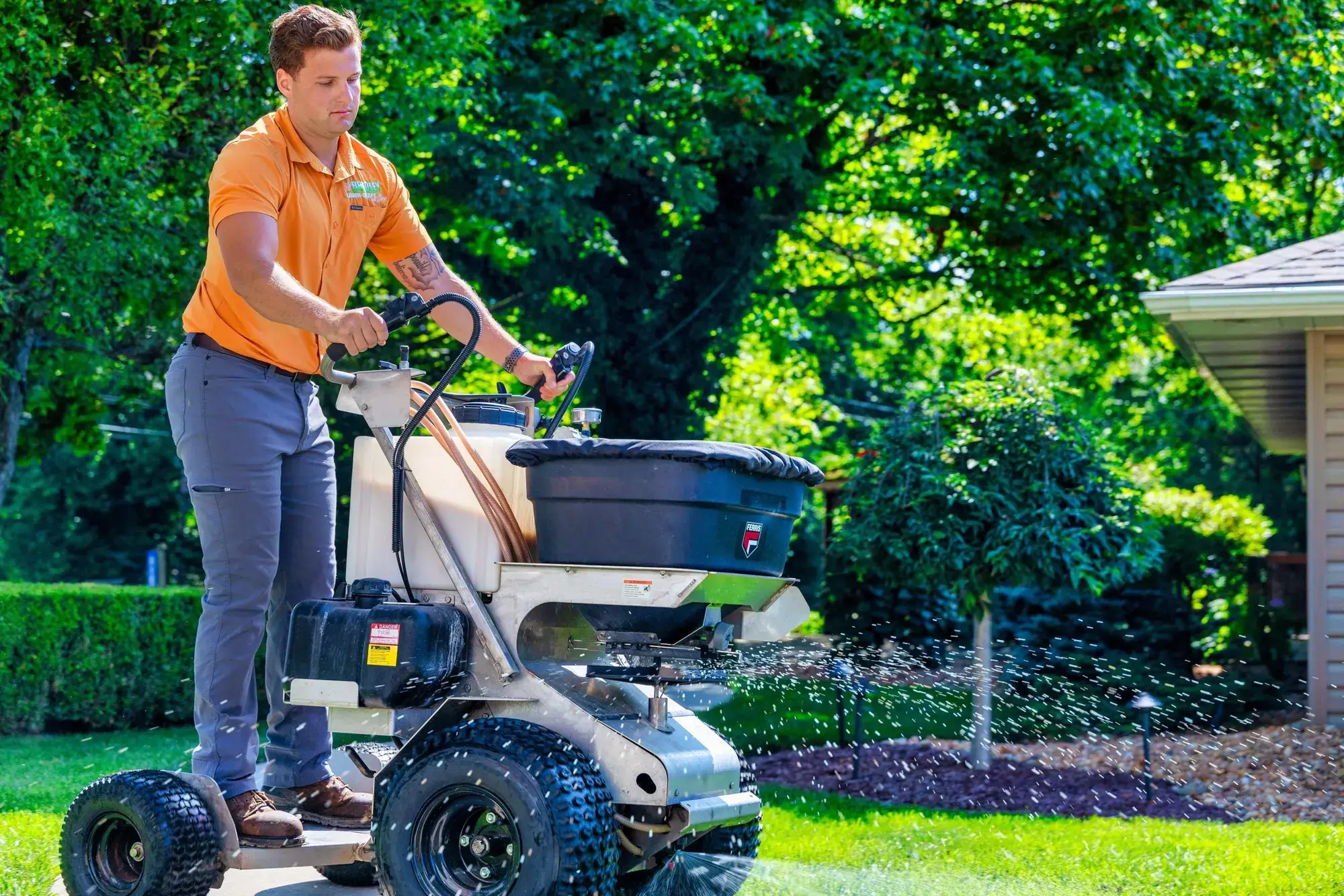 Technician applying fertilizer with a spreader