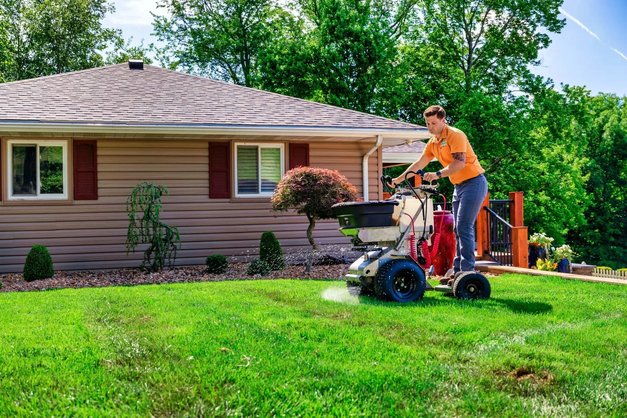 Bradley Lawn-Scape technician fertilizing a front lawn with a spreader