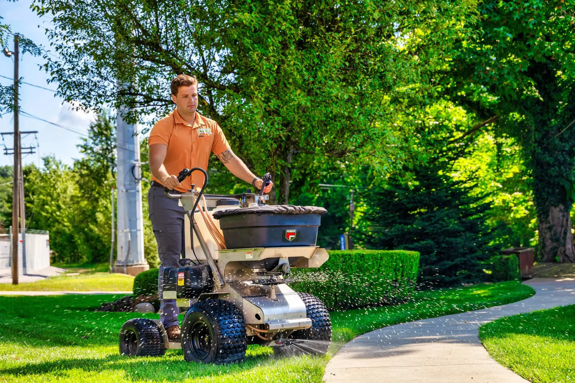 Technician applying lawn fertilizer with a spreader